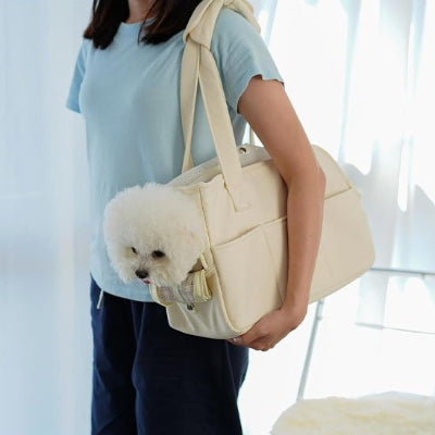 femme portant son petit chien blanc dans son chien sac de transport Premium Canin écru 