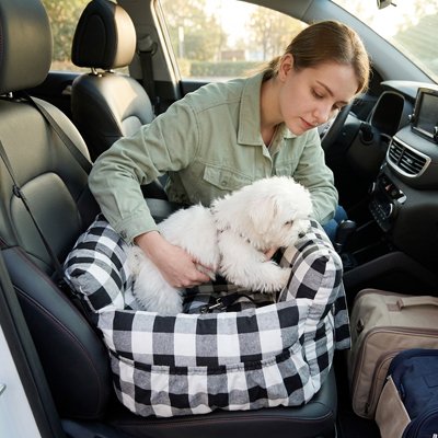 femme posant un chien dans un siege auto pour chien Toutou mobile à carreaux