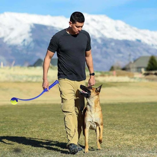 homme en montagne avec son chien et un lanceur de balle pour chien Launchy bleu