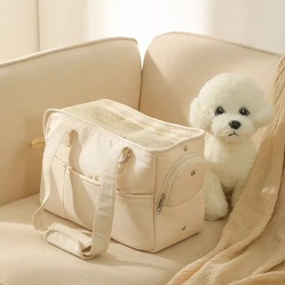 Petit chien blanc assis à coté de son chien sac de transport Premium Canin écru